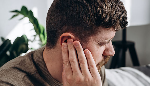 man holding his ear in discomfort